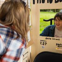 Two students interact between hand drawn photo booth at Student Small Business Market.